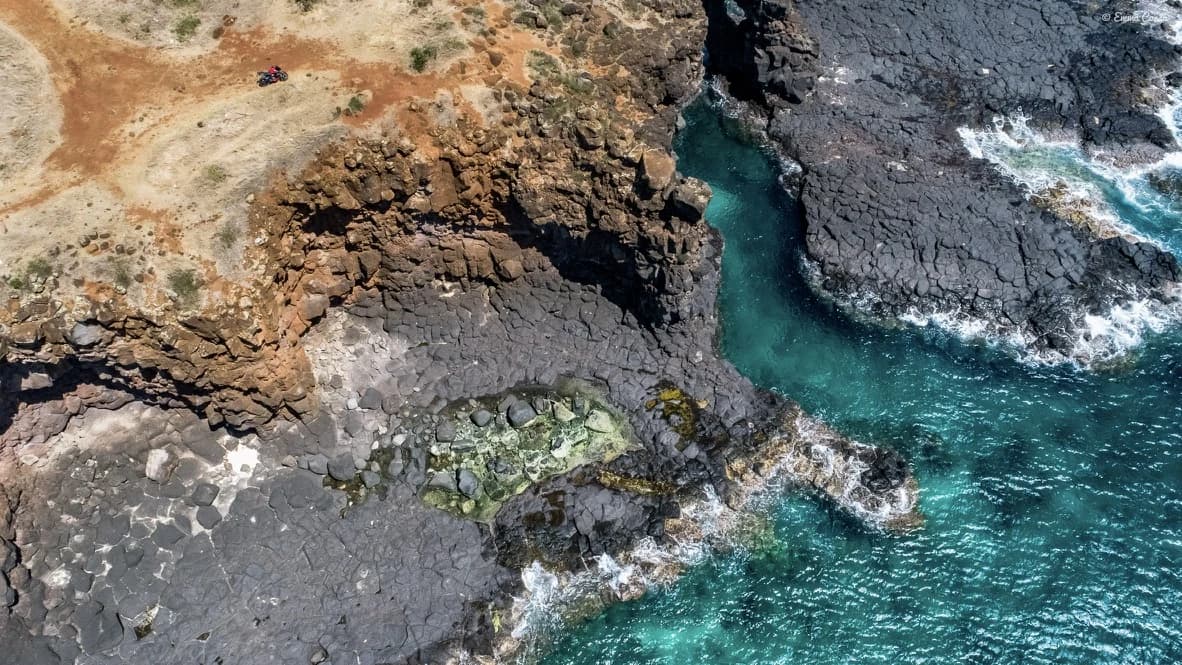 Aerial view of clear water cutting through a rocky coast